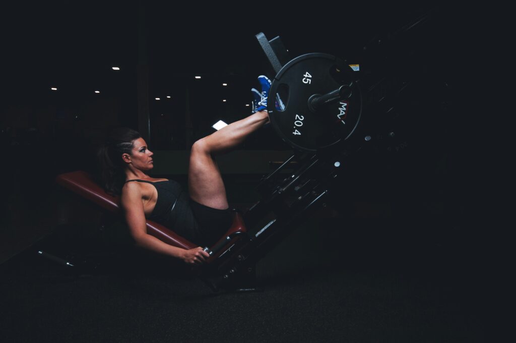 A woman performing a leg press on a weight machine in a gym.