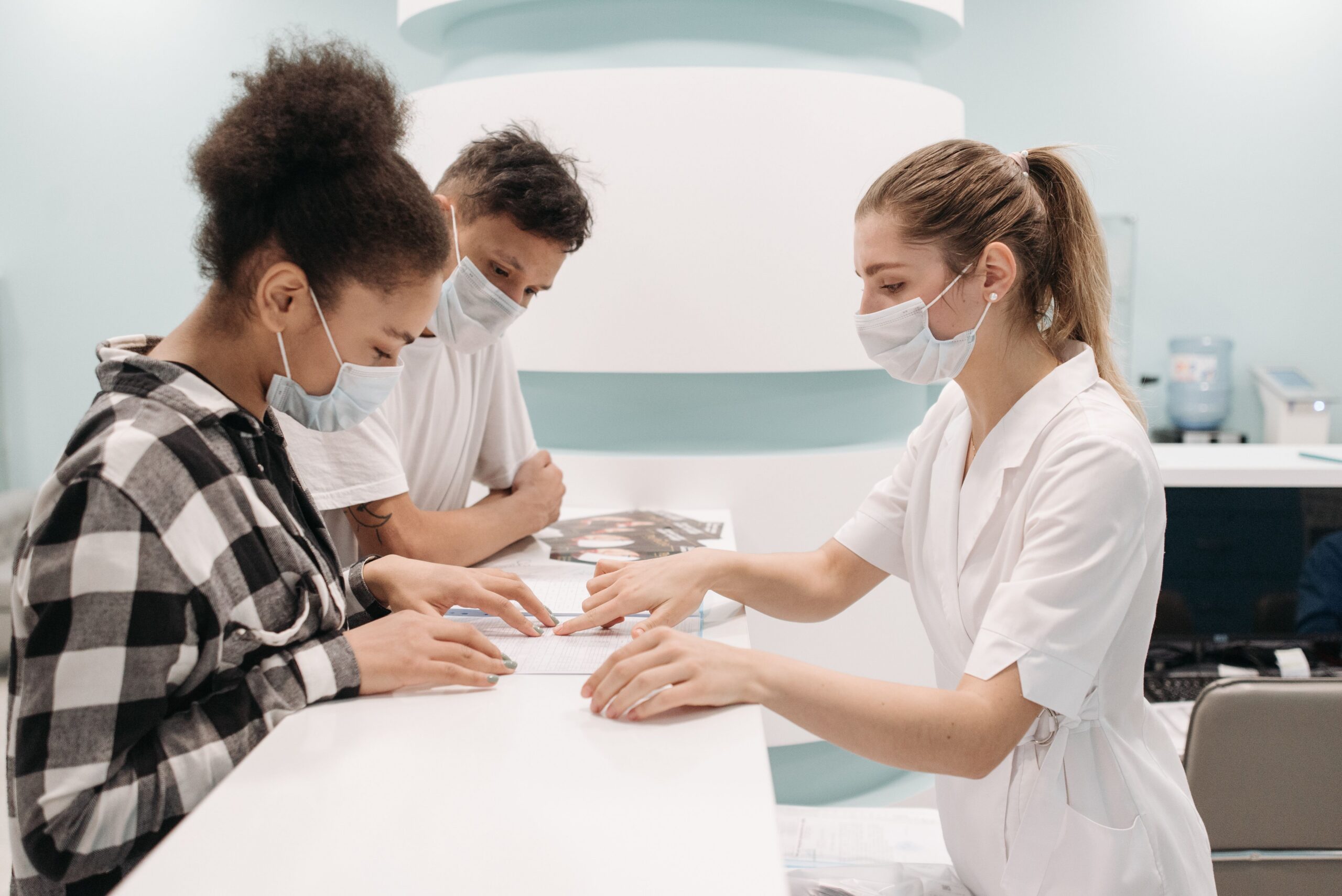 TRT vs clomiphene: couple reviewing fertility treatment paperwork with a clinic staff member at the front desk