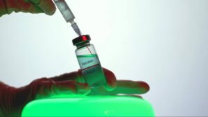healthcare professional holding a vaccine vial and syringe during an injection preparation