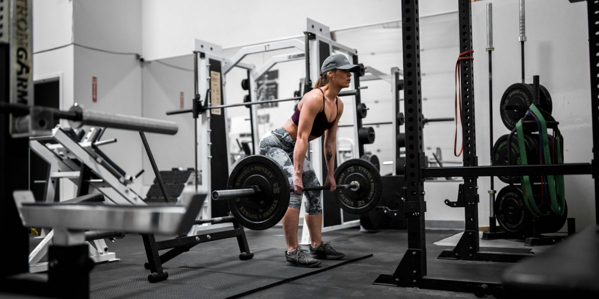 A woman performing a barbell deadlift in a professional gym.